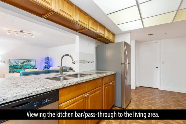 a kitchen with stainless steel appliances granite countertop a sink a refrigerator and a granite counter tops