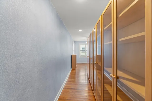 a view of an empty room with window and wooden floor