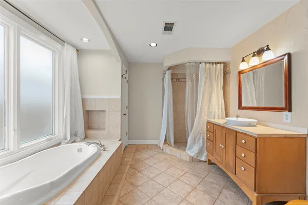 a bathroom with a granite countertop tub sink and mirror