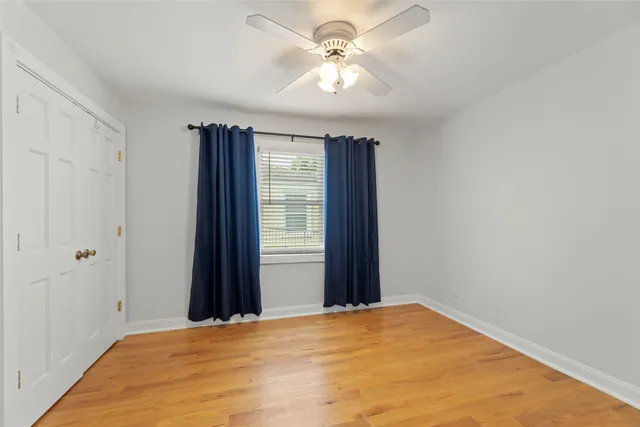 an empty room with wooden floor and ceiling fan