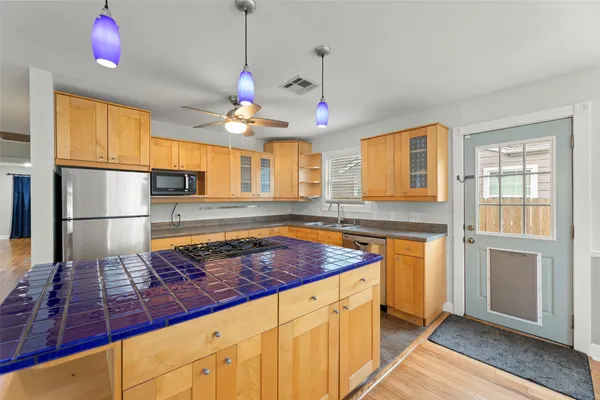 a kitchen with kitchen island granite countertop a stove a sink a refrigerator dining table and chairs