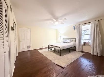 a spacious bedroom with a bed and wooden floor