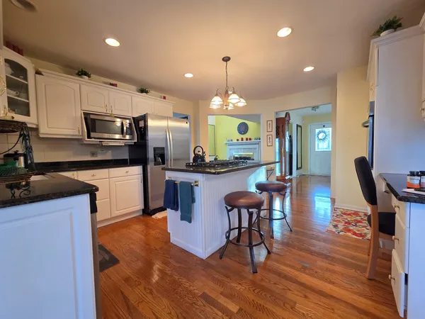 a kitchen with stainless steel appliances a dining table chairs stove refrigerator and cabinets
