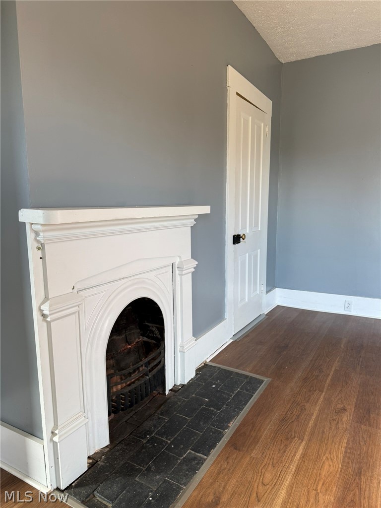 23033 Cadiz Road Freeport, OH 43973 - Photo 20 of 31 Detailed view of wood finished floors, a textured ceiling, and a fireplace with flush hearth