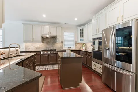 a kitchen with stainless steel appliances granite countertop a refrigerator and a stove