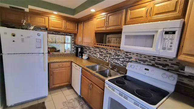 a kitchen with granite countertop a sink stove and refrigerator