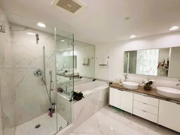 a bathroom with a tub sink double vanity and mirror