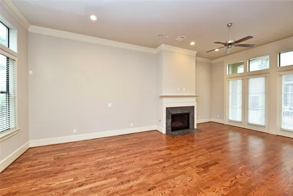 a view of an empty room with wooden floor fireplace and a window