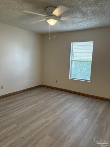 an empty room with wooden floor fan and windows