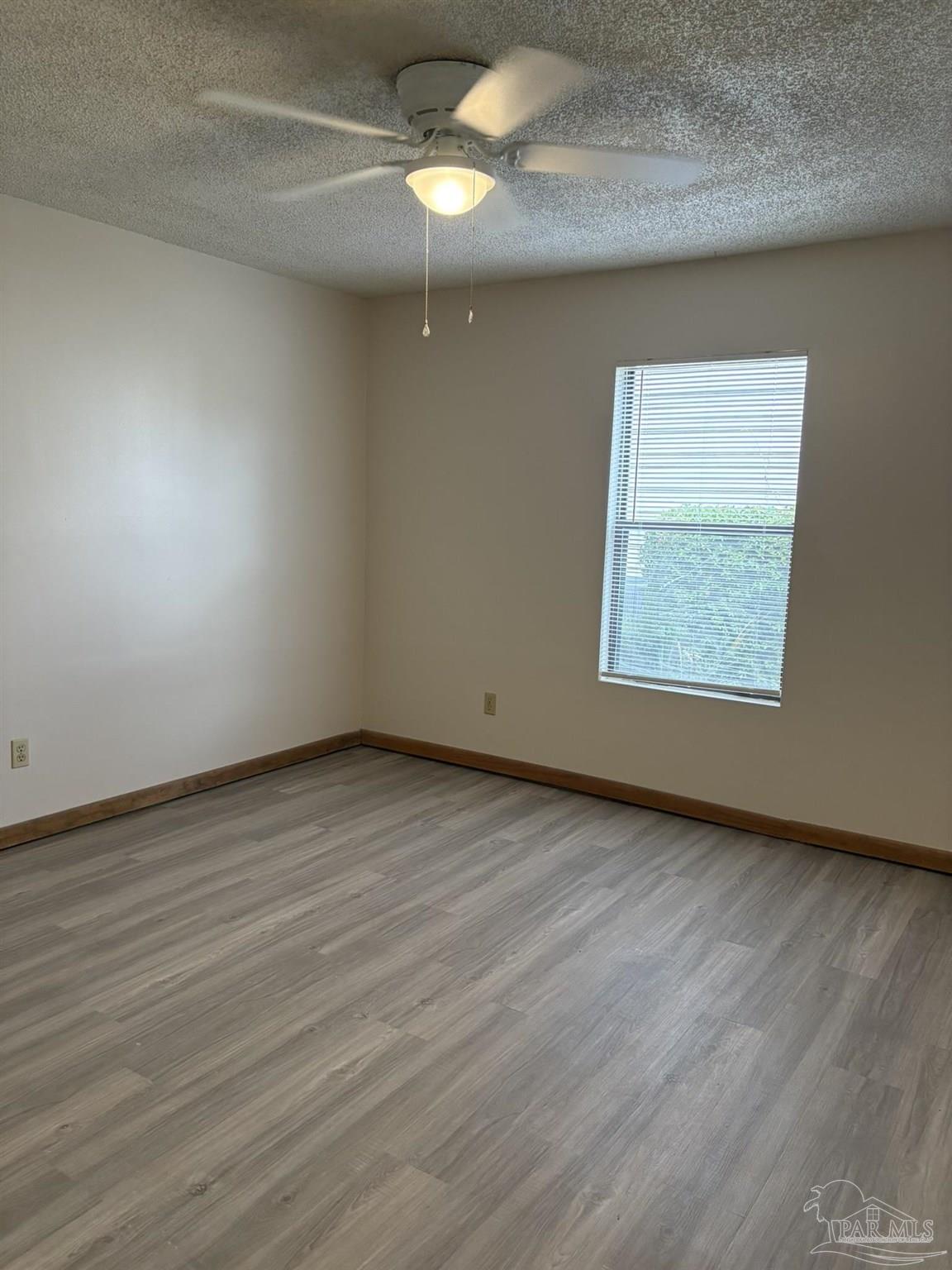 3262 Maplewood Drive, Unit B Gulf Breeze, FL 32563 - Photo 13 of 15 an empty room with wooden floor fan and windows