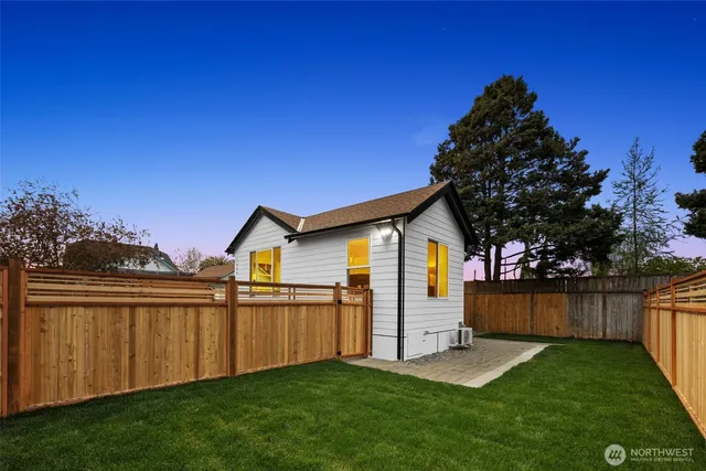 a view of a backyard with wooden fence and large trees