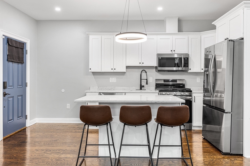 128 Hamilton Street, Unit 2B Boston, MA 02125 - Photo 8 of 23 a kitchen with stainless steel appliances granite countertop a stove a sink dishwasher a refrigerator with a dining table and chairs