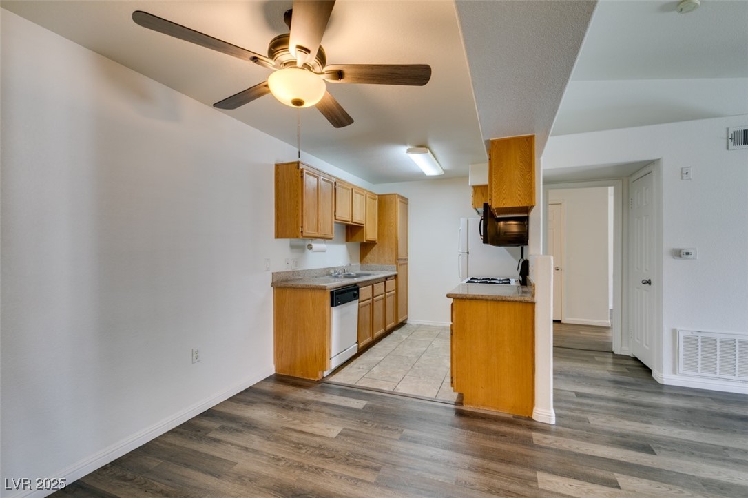 3318 North Decatur Boulevard, Unit 2138 Las Vegas, NV 89130 - Photo 19 of 40 Kitchen with white dishwasher, light wood-style flooring, ceiling fan, a sink, and baseboards