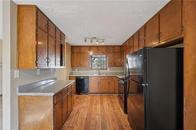 a kitchen with stainless steel appliances granite countertop a refrigerator a sink dishwasher a stove and a refrigerator