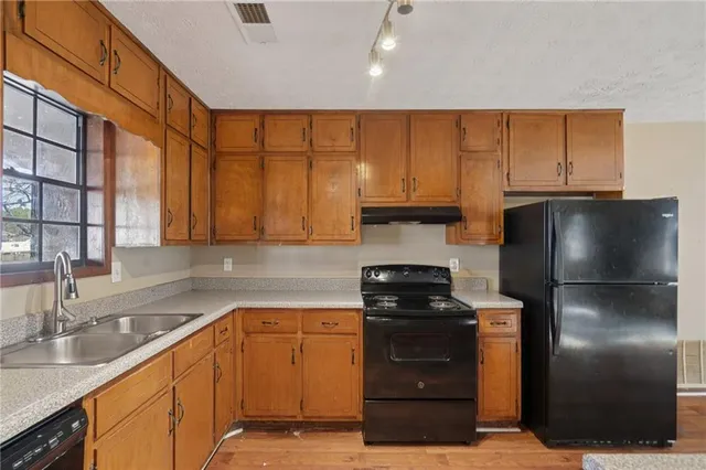 a kitchen with stainless steel appliances granite countertop a refrigerator a stove and a sink with cabinets