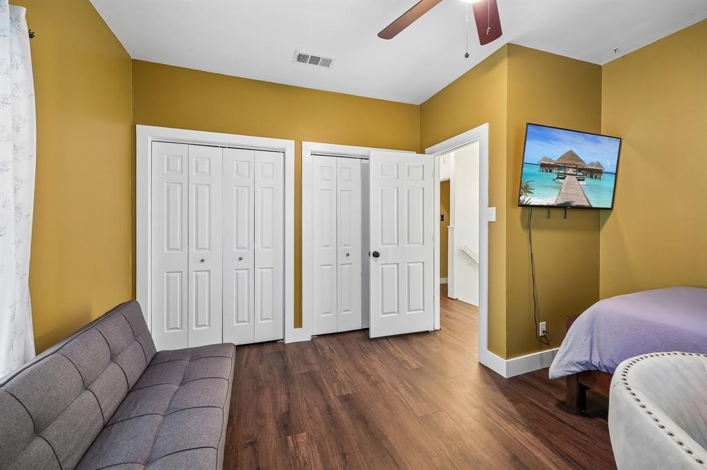 331 Radecke Road Krum, TX 76249 - Photo 28 of 40 Room featuring wood-finish flooring, two sets of bi-fold closet doors, a white interior door, and a ceiling fan with integrated lighting