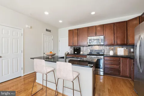 a kitchen with stainless steel appliances granite countertop a stove top oven a sink dishwasher and white cabinets with wooden floor