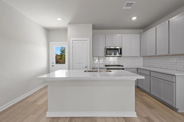 a kitchen with kitchen island sink stove and cabinets