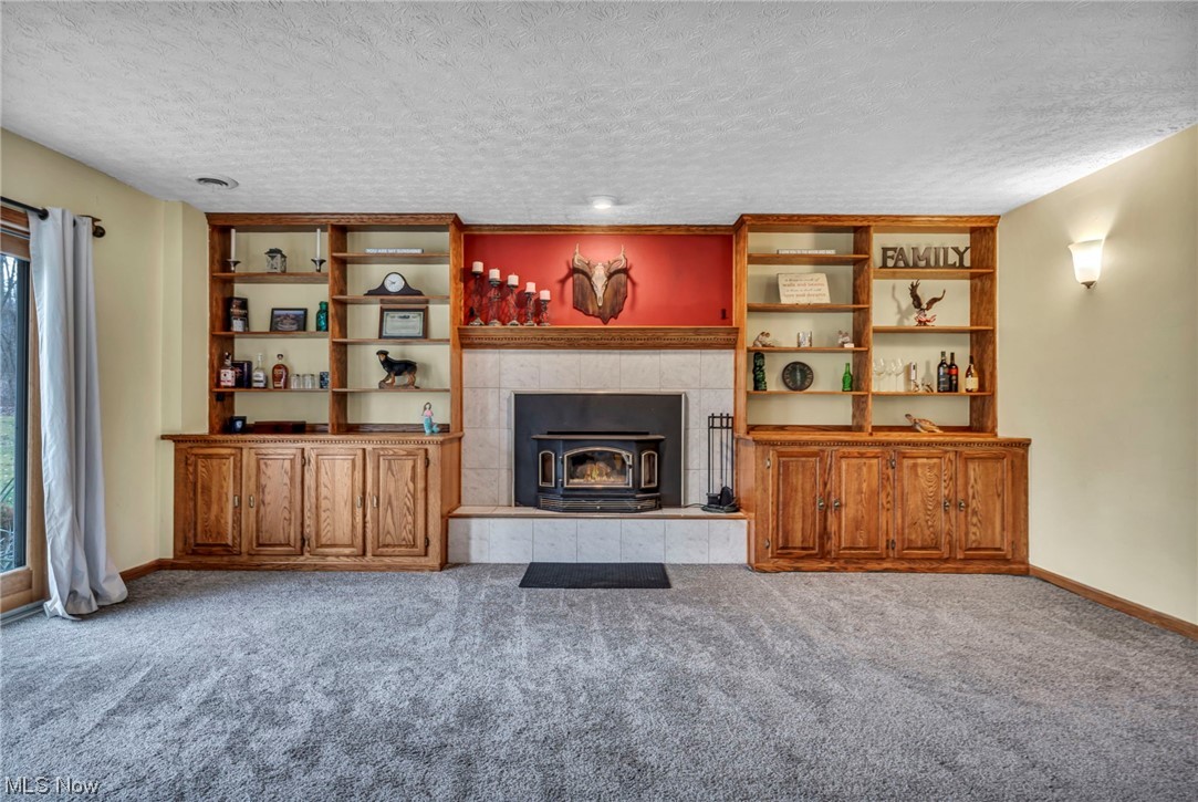 3324 Poe Road Medina, OH 44256 - Photo 11 of 26 Unfurnished living room with plenty of natural light, light carpet, a textured ceiling, and a tiled fireplace
