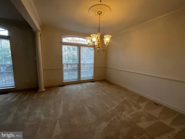 a view of an empty room with window and chandelier fan
