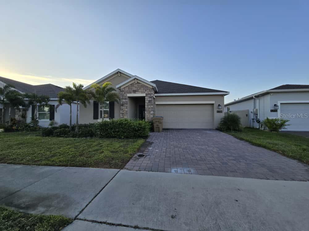 6336 Chirpine Lane St. Cloud, FL 34771 - Photo 2 of 3 a front view of a house with a yard and garage