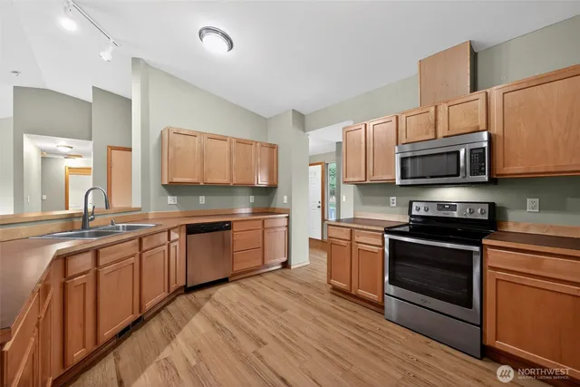 a kitchen with stainless steel appliances granite countertop wooden cabinets a stove top oven a sink and dishwasher