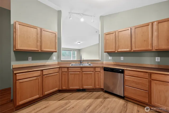 a kitchen with granite countertop wooden cabinets a sink and dishwasher