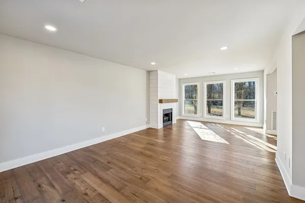 a view of empty room with wooden floor and floor to ceiling window