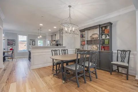 a kitchen with stainless steel appliances granite countertop a stove top oven a sink dishwasher a dining table and chairs with wooden floor