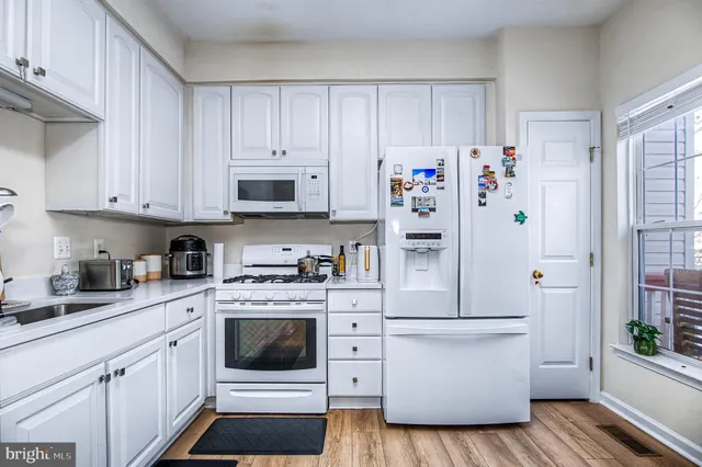 a kitchen with granite countertop white cabinets and white appliances