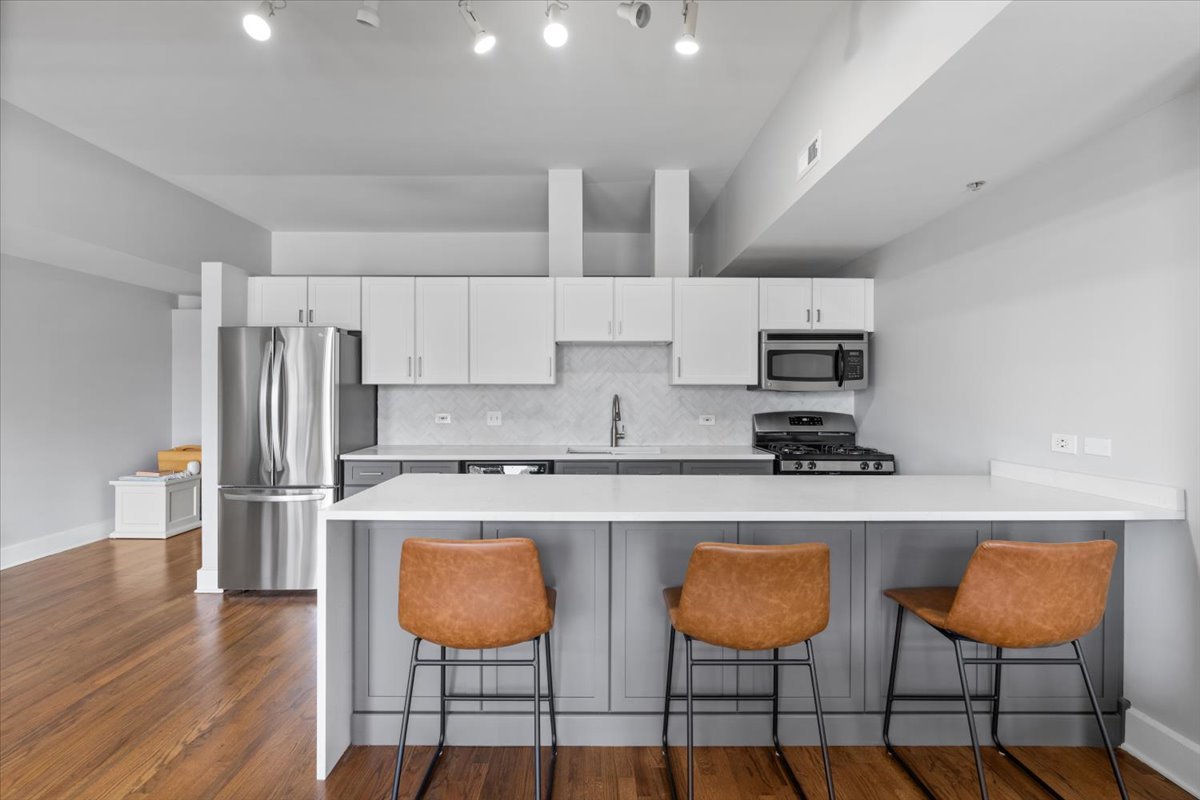 165 North Canal Street, Unit 706 Chicago, IL 60606 - Photo 5 of 27 a kitchen with stainless steel appliances granite countertop a table chairs refrigerator and sink