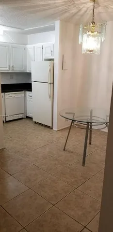 a view of a refrigerator in kitchen and an empty room