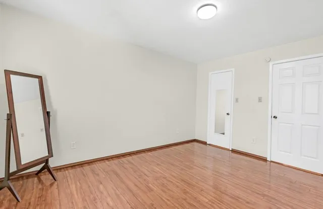 a view of an empty room with wooden floor and a window