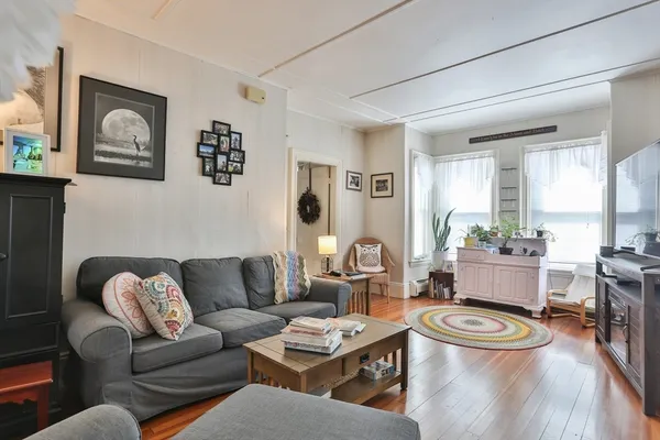 a living room with furniture and a dining table with wooden floor