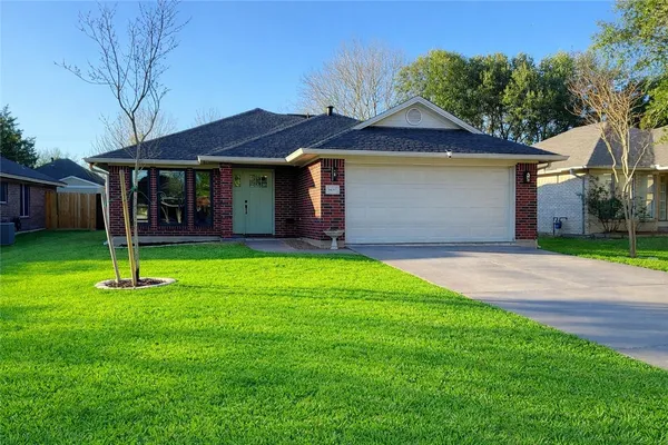 a front view of a house with plants and large tree