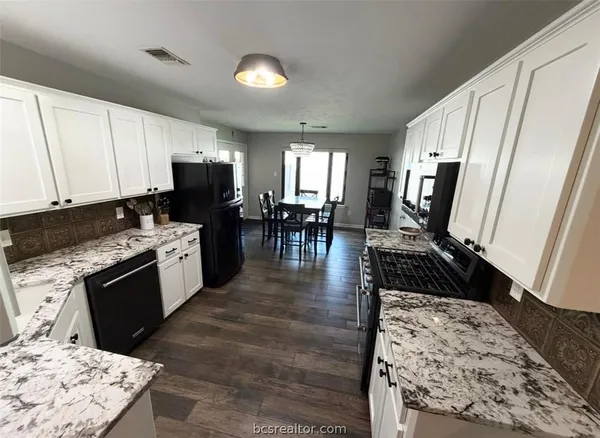 a kitchen with granite countertop white cabinets and sink
