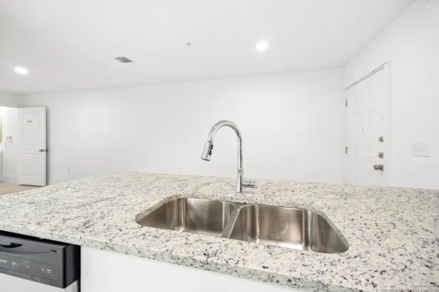 a kitchen with granite countertop white cabinets and stainless steel appliances