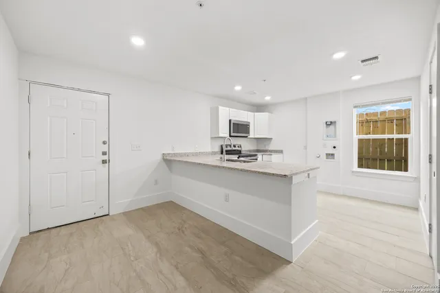 a kitchen with granite countertop a sink a counter top space cabinets and stainless steel appliances