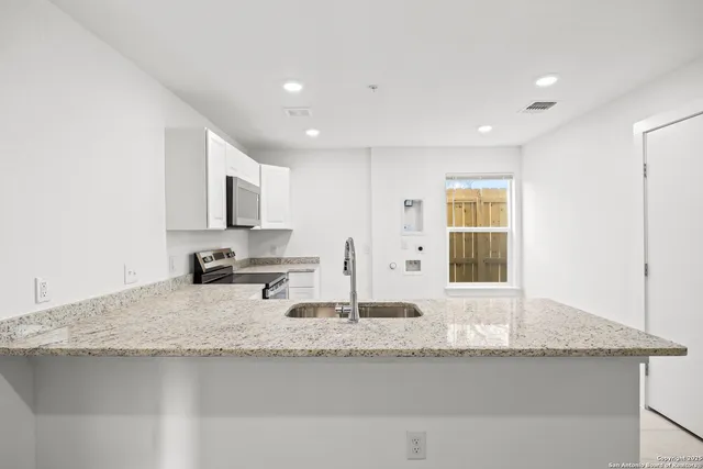 a kitchen with granite countertop white cabinets and appliances