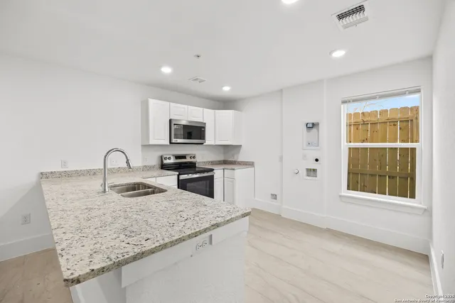 a kitchen with granite countertop white cabinets and white appliances