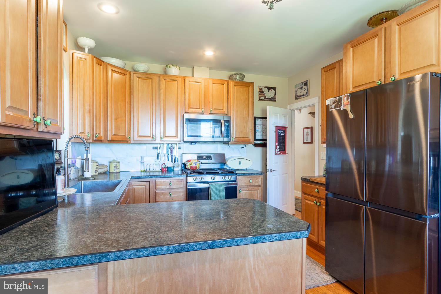 321 Mount Nittany Road Lemont, PA 16851 - Photo 10 of 43 a kitchen with stainless steel appliances granite countertop a refrigerator a stove and a sink with wooden cabinets