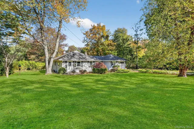 a view of a house with a yard and a lot of flower plants