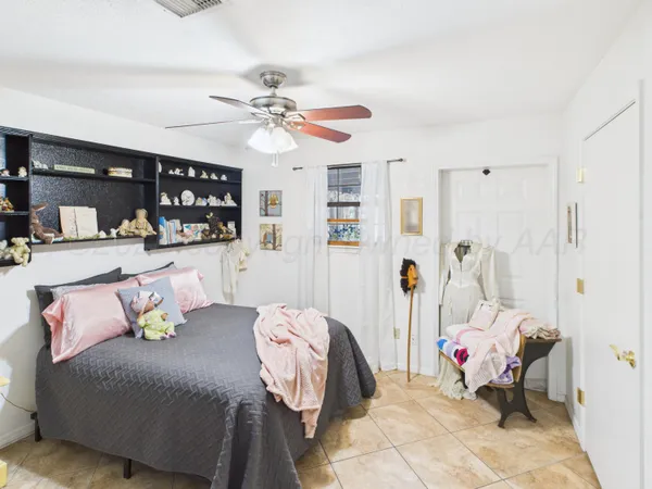 a spacious bedroom with a bed a couch and painting on the wall