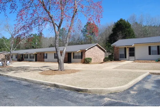 a view of a white house with a yard and large tree