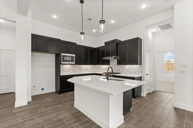 a large kitchen with stainless steel appliances kitchen island granite countertop a sink a stove and a refrigerator