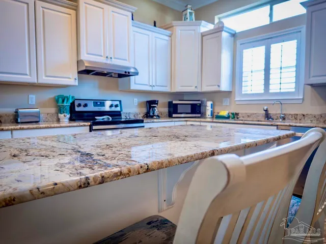 a living room with furniture kitchen view and a chandelier