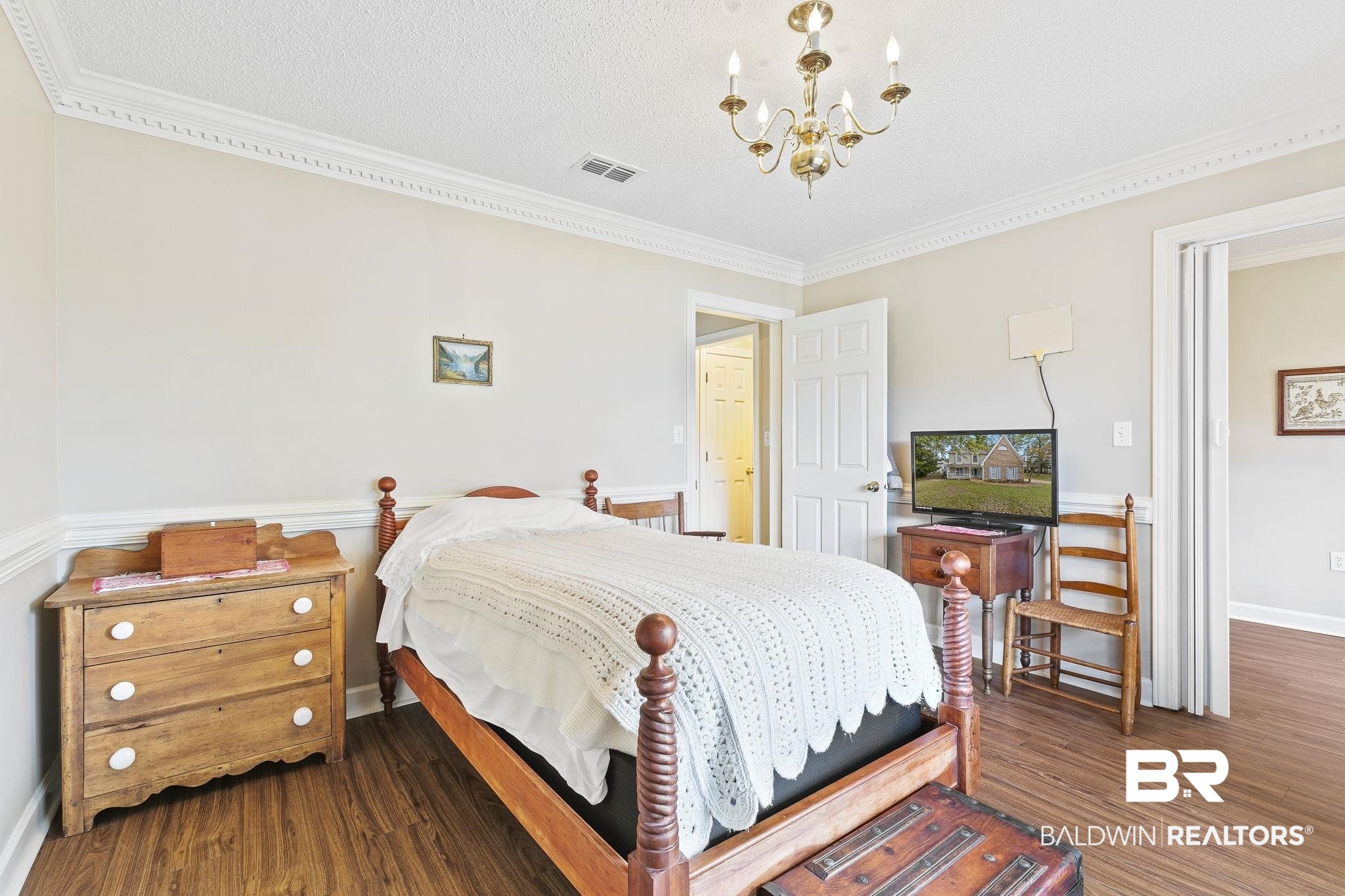 22 Pirates Lane Daphne, AL 36527 - Photo 11 of 36 Bedroom featuring a textured ceiling, dark hardwood / wood-style floors, an inviting chandelier, and crown molding