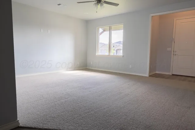 an empty room with a window and a ceiling fan