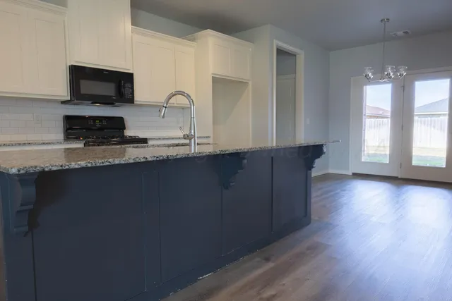 a kitchen with granite countertop a stove a sink and a microwave