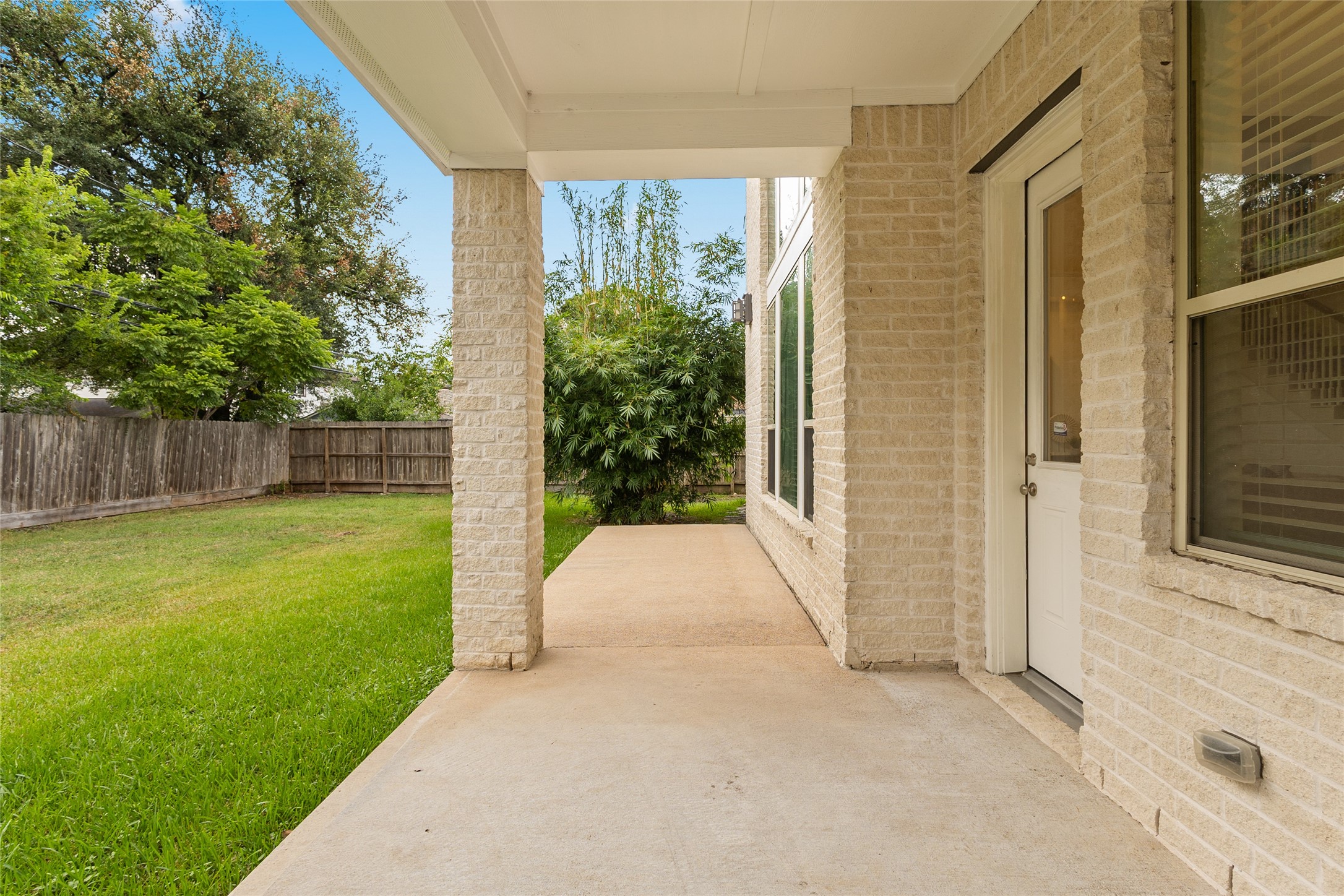3302 Rochdale Street Houston, TX 77025 - Photo 47 of 50 Have a look at your covered back patio, offering a shaded spot to relax while overlooking the spacious, fully fenced backyard. Mature trees and greenery add privacy along the perimeter, while the extended concrete slab provides plenty of room for outdoor furniture or entertaining. It's a versatile outdoor space ready for morning coffee, weekend barbecues, or quiet evenings outside.